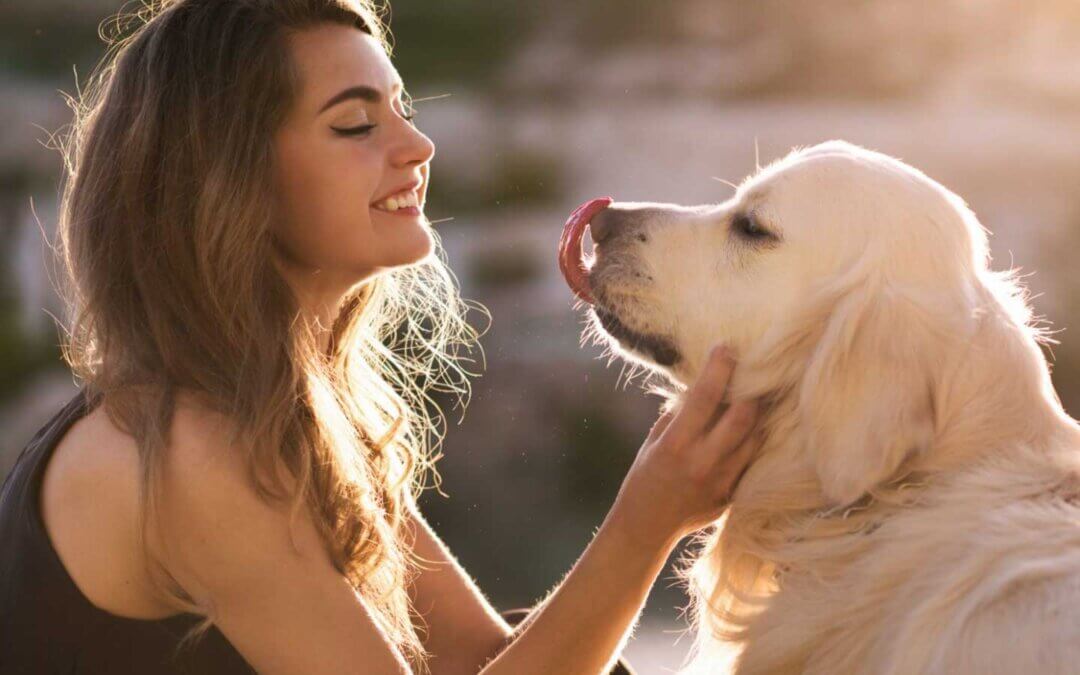 A photo of a women smiling looking at a dog licking his nose