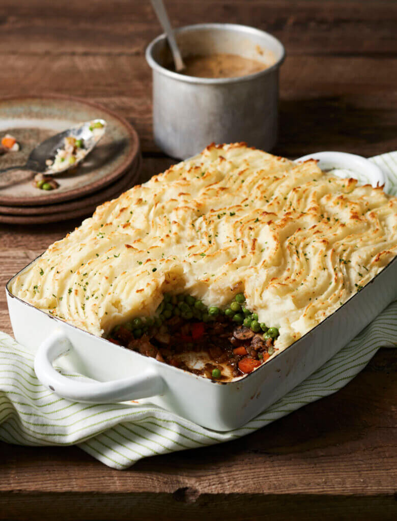 A lentil shepherd's pie on a harvest table, with a slice taken out of it.
