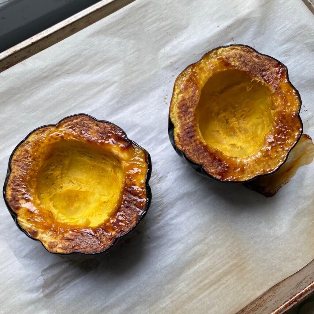 An acorn squash has been cut open and have been placed on a baking tray to be roasted.