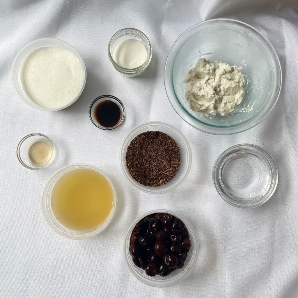 An assembly of ingredients to make a plant-based cherry chocolate pavlova.